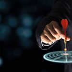 Unlocking the Secret to Fulfilling Your True Goals This Year Hand aiming dart at digital target.