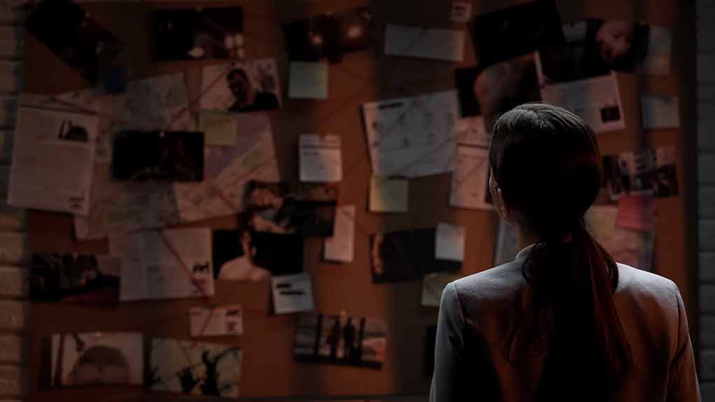 Person examining a bulletin board with documents and photos.