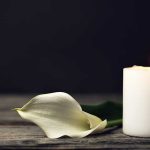 Deadly Incident in Mexico Involves Americans, Leaves One Critically Hurt White candle and calla lily on wooden surface.
