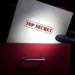 Gloved hand holding top secret document in file drawer