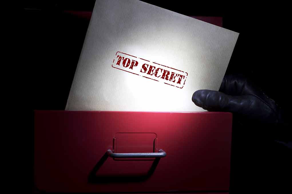 655887151 featured image Gloved hand holding top secret document in file drawer