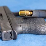 Handgun on blue fabric with visible bullet cartridge.