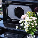 Colorful flowers on a black tombstone.