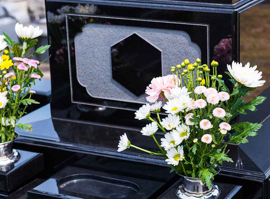 Colorful flowers on a black tombstone.