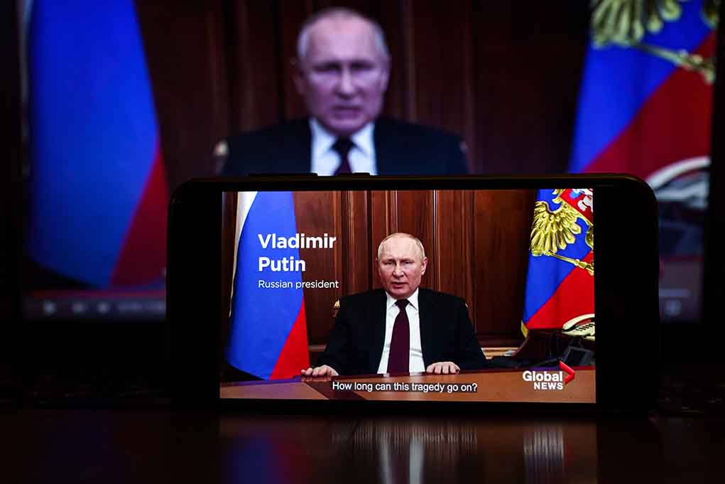 Man speaking on screen with Russian flag background