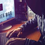 Hacker typing at desk with Cyber War screen