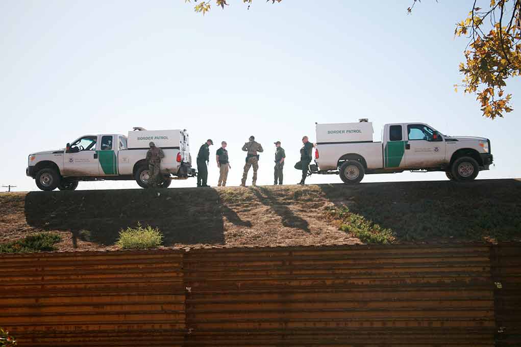 Border Patrol vehicles and agents on a ridge