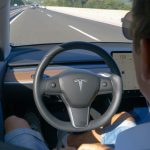 Person in Tesla car using autopilot on highway.
