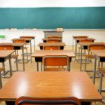 Classroom with wooden desks and empty green chalkboard