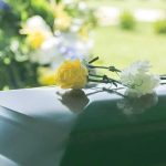 GUT WRENCHING HORROR—Sirens Silent, Families Gone Yellow and white flowers on a green casket