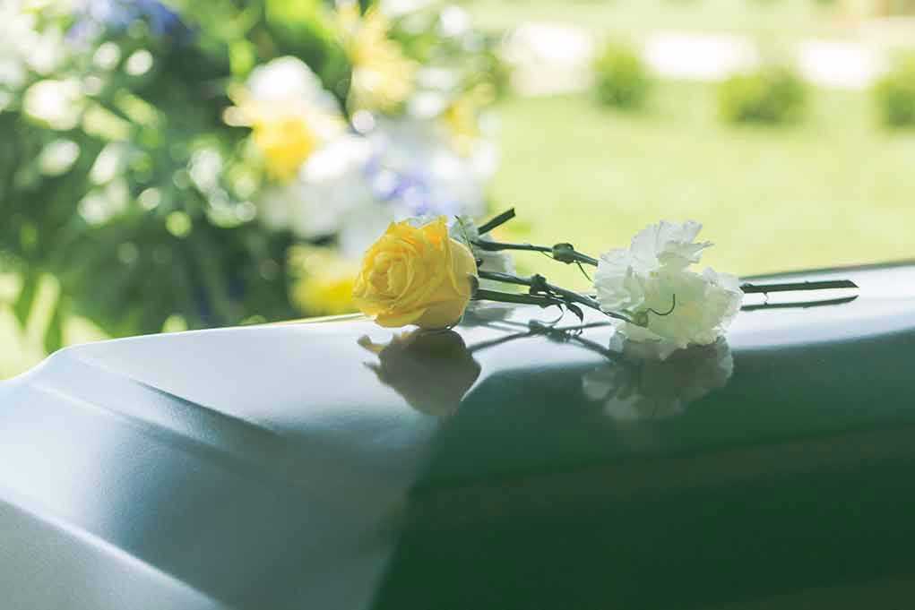 Yellow and white flowers on a green casket