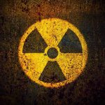 Nuclear Tensions EXPLODE: Iran’s Next Move? Yellow radiation warning symbol on rusty metal surface