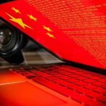 Chinese Spy’s Guilty Plea Rocks US Security Laptop screen displaying Chinese flag and code