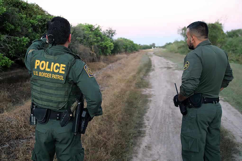 Two Border Patrol officers observing a dirt path