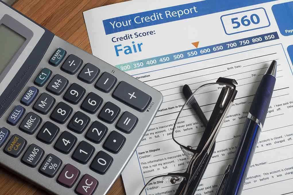 Calculator and glasses on credit report document