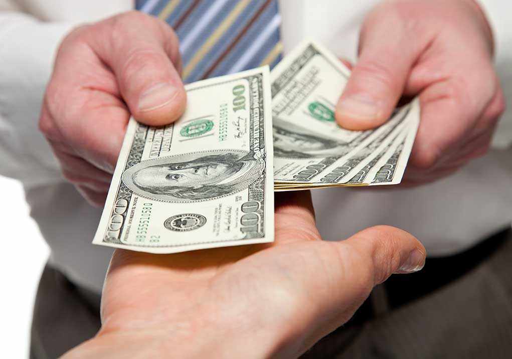 Two hands exchanging cash bills in a business context