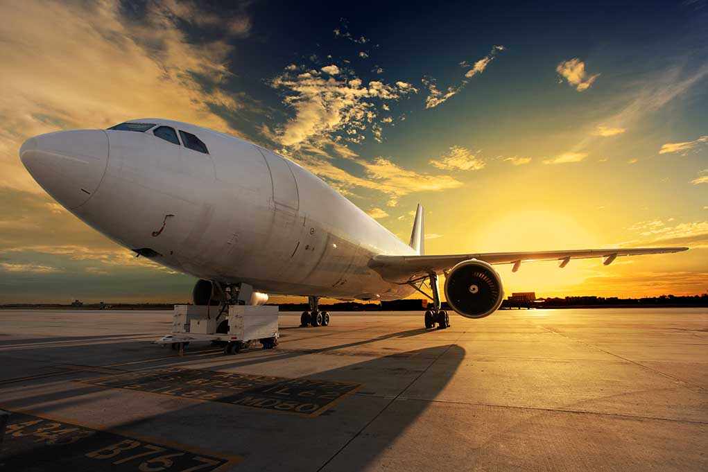 An airplane parked on the runway during sunset with a colorful sky
