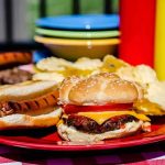 Grill Shock: Carcinogens Lurking in Your Food A plate with a hamburger, hot dog, and potato chips on a picnic table