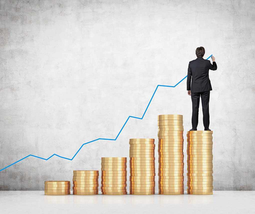 shutterstock_221639947.jpg Businessman standing on stacks of coins, drawing a growth chart