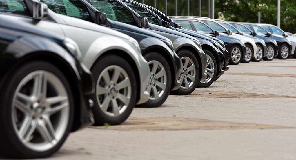 A row of parked black and silver cars in a dealership