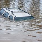 Flood BLAME GAME Erupts—Complete CHAOS A partially submerged vehicle in floodwaters