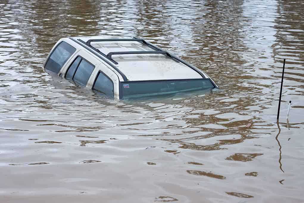 A partially submerged vehicle in floodwaters