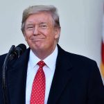 Biden Appointee Caught–Shock Criminal Referral Man in suit and tie speaking at podium