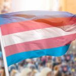Trans-Terrorism Label Ignites Nation – Fiery Debate! Transgender pride flag waving at outdoor event.
