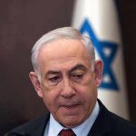 Netanyahu Drops MAGA Bomb—Conservatives Erupt Man in suit with Israeli flag in background.