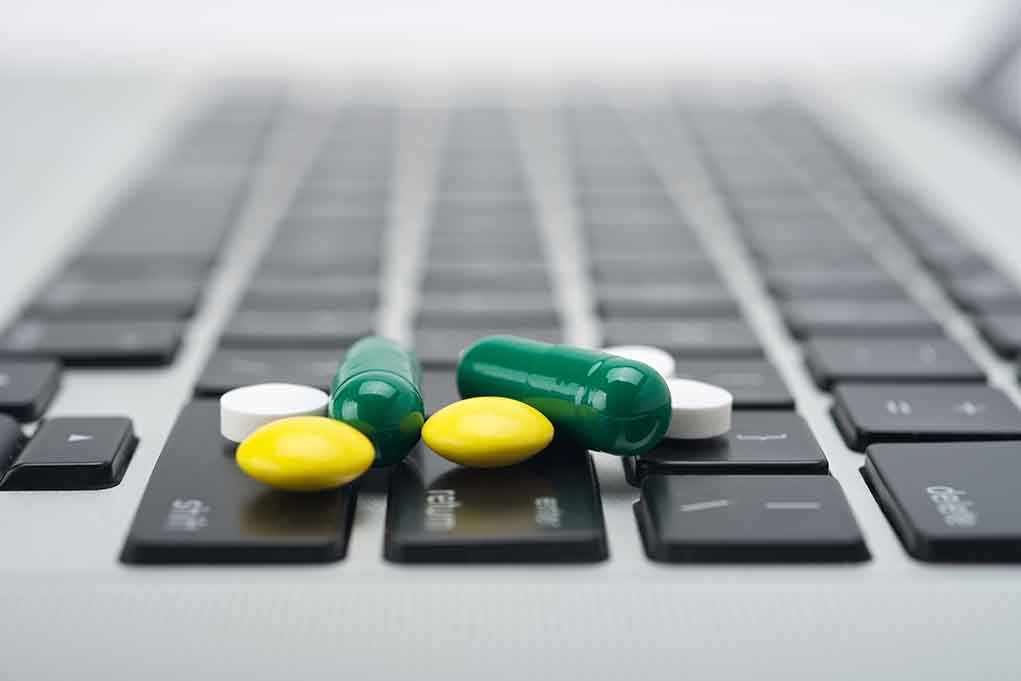 Various colored pills scattered on a laptop keyboard