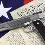 2A Threatened – New Ban PROPOSED! A handgun placed on top of the U.S. Constitution and an American flag
