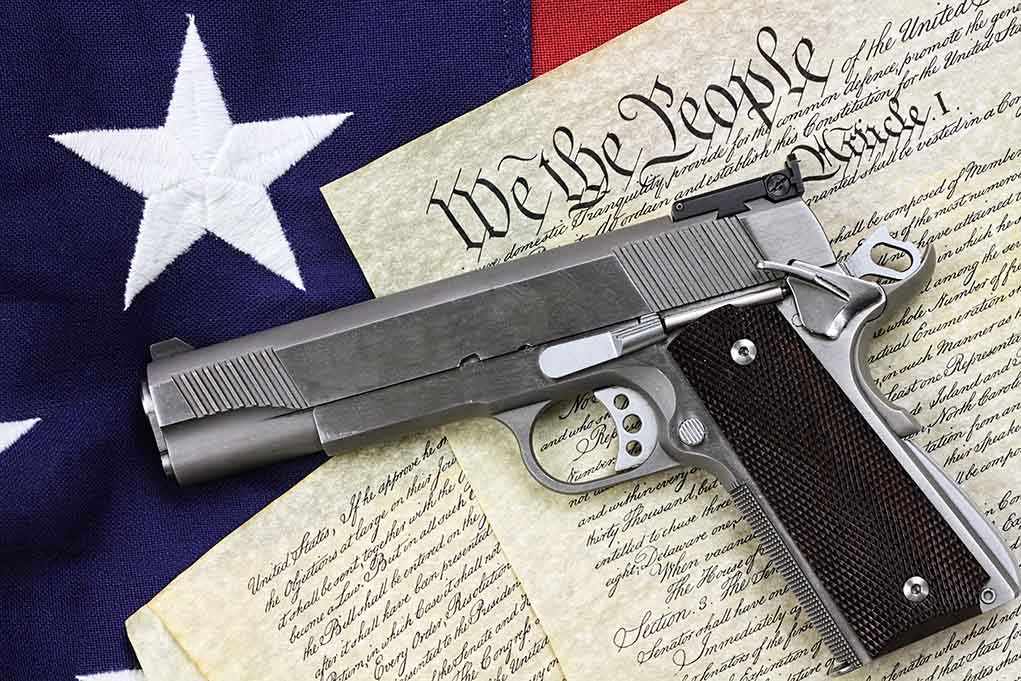 A handgun placed on top of the U.S. Constitution and an American flag