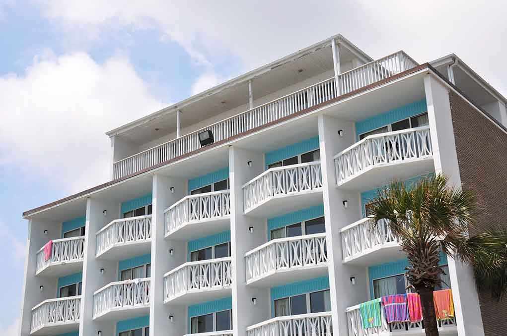 Exterior view of a beachfront hotel with balconies and colorful towels hanging