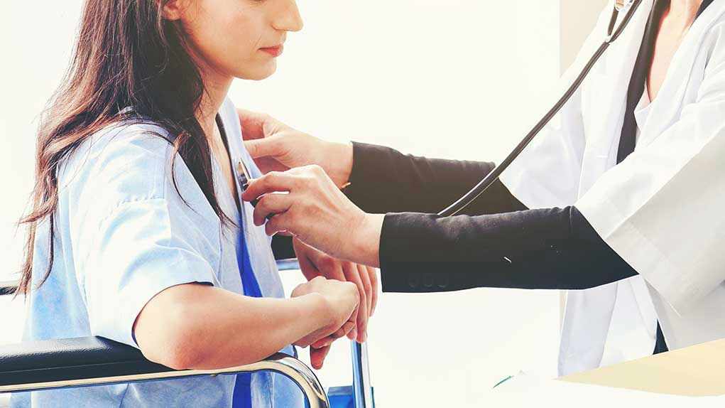 Doctor examining patient with stethoscope in hospital