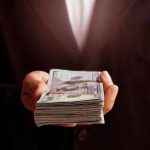 Investor DISAPPEARS With Magazine Fortune Hand holding a stack of hundred dollar bills