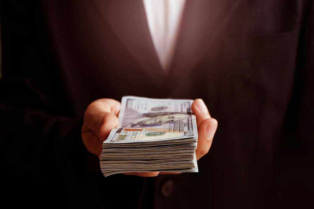 Hand holding a stack of hundred dollar bills