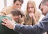 Group comforting a distressed person with hand on shoulder