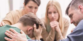 Group comforting a distressed person with hand on shoulder