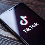 TRUMP FORCES China TikTok Surrender Deal Phone screen showing TikTok logo and app