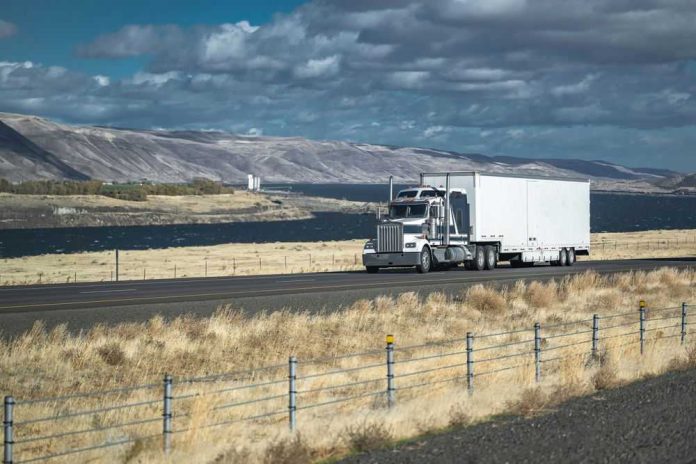 2262168801 Truck driving on rural highway near river and mountains
