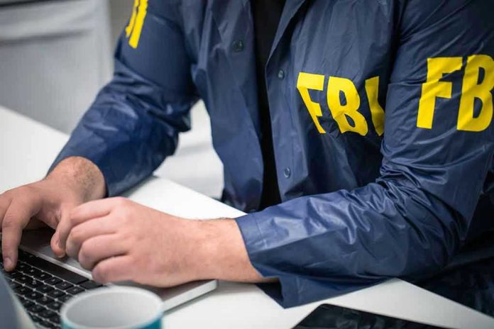 Person in FBI jacket typing on a laptop