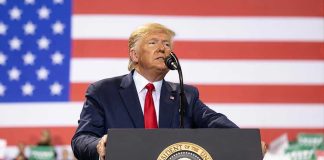 Trump-Greene MELTDOWN — MAGA Implodes on Live TV Man speaks at podium with U.S. flag background.