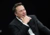 Musk’s TRILLION Payday STUNS Experts Man in suit smiling resting chin on hand