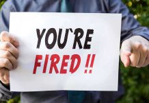 Fired and Rehired at LOWER Pay – Outrageous! Person holding YOURE FIRED sign.