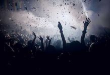 Crowd celebrating under confetti and bright lights