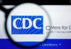 Newborns Lose Shield After Stunning CDC Reversal CDC logo magnified on a screen.