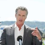 Man speaking with microphone outdoors.