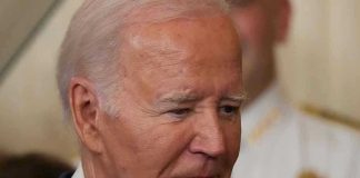 Trump Cuts Security for Bidens Man in a suit looking thoughtful.