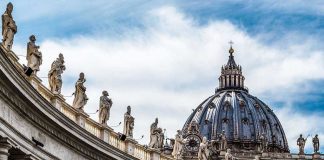 VATICAN ADVANCES Sainthood For Child Abuse Bishop St. Peters Basilica dome with statues and clouds.