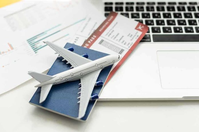 A model airplane on a blue passport next to a laptop and boarding pass